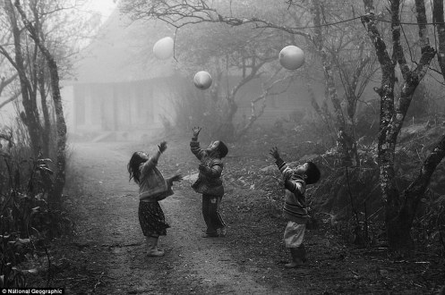 Vo Anh Kiet H'Mong minority children were playing with their balloons on the foggy day in Moc Chau - Ha Giang province Viet Nam in January 2012.